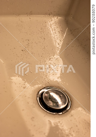Small pieces of hair left in a bathroom sink after a man finished shaving in the morning. 90288079