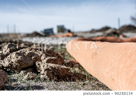 selective focus on filter sock around exposed dirt at a construction site to prevent stormwater erosion and runoff  90288134
