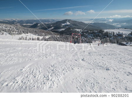 Winter snow covered mountain ski resort slope . Magnificent sunny day on picturesque alpine resort, Dragobrat, Ukraine, Carpathian Mountains. People unrecognizable. 90288201