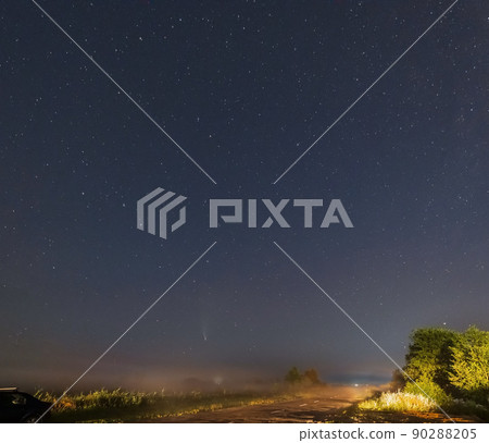 Comet Neowise C2020 F3 as it flies overhead in the summer sky over over meadow near countryside road, Lviv Region, Ukraine. 90288205