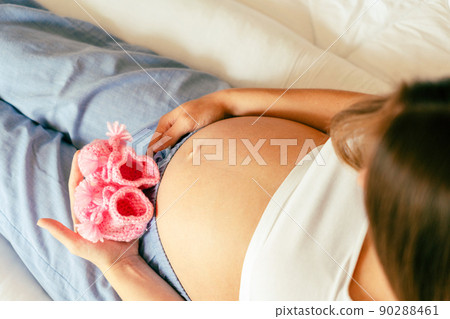 Children shoes pregnancy woman. Beautiful pregnant woman holding pink baby shoes. Waiting for baby. Pregnancy, maternity concept. 90288461