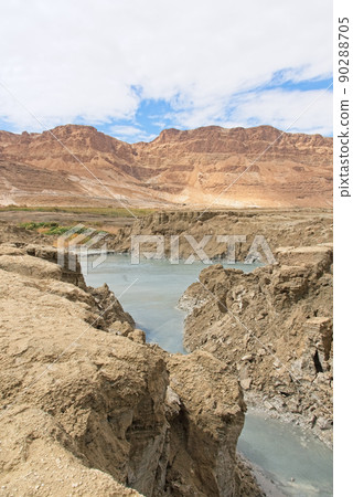 Sinkhole filled with turquoise water, near Dead Sea coastline. Hole formed when underground salt is dissolved by freshwater intrusion, due to continuing sea-level drop.  90288705