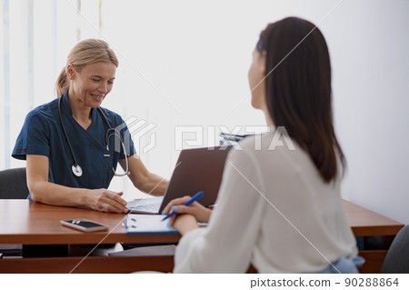 Female patient writes down the doctor's recommendations during appointment in clinic 90288864
