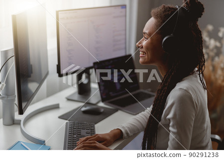 Close up shot of positive beautiful female listening to music in headphones browsing on computer Close up shot of positive beautiful female listening to music in headphones browsing on computer 90291238