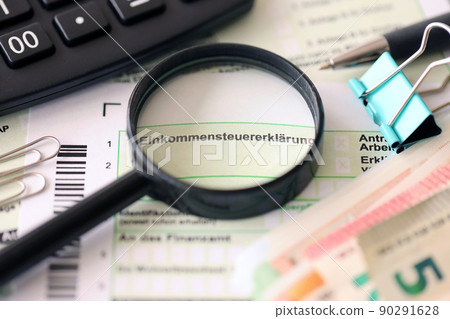 German income tax return form with pen and european euro money bills lies on accountant table close up. Taxpayers in Germany using euro currency to pay taxes 90291628