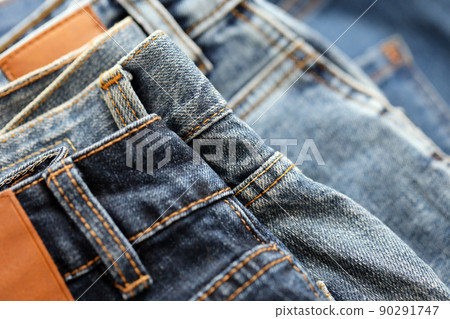 Many jeans in stack in wardrobe room. Row of pants denim jeans in closet. Concept of buy, sell, shopping and fashionable clothes 90291747