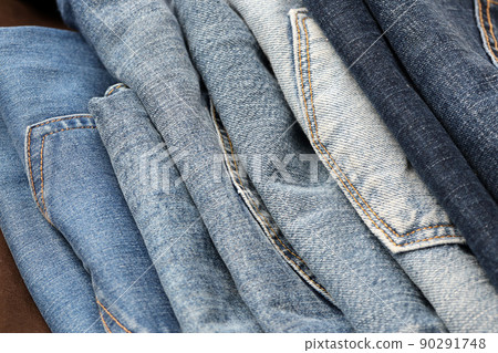 Many jeans in stack in wardrobe room. Row of pants denim jeans in closet. Concept of buy, sell, shopping and fashionable clothes 90291748
