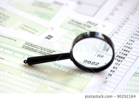 German different tax forms and magnifying glass pointed on 2022 inscription. The concept of taxpaying perion 90292164