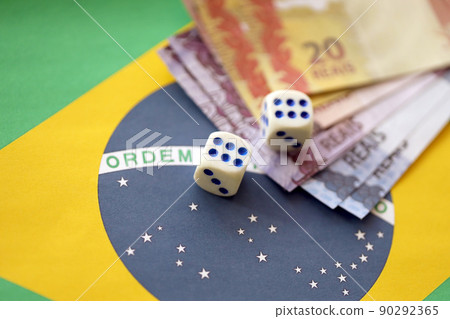 Dice cubes with brazilian money bills on flag of Brasil Republic. Concept of luck and gambling in Brasil 90292365