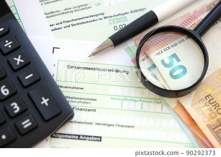 German income tax return form with pen and european euro money bills lies on accountant table close up. Taxpayers in Germany using euro currency to pay taxes 90292373