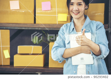 Asian woman startup small business at home office. Online seller entrepreneur young asian woman use tablet checking online order. Woman using tablet check stock goods supply delivery package shipping 90293402