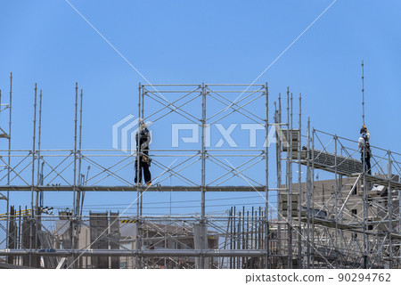 Workers erecting scaffolding at a construction site Workers erecting scaffolding at a construction site 90294762