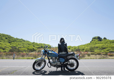 A young woman touring image with a motorcycle parked and looking at the scenery A young woman touring image with a motorcycle parked and looking at the scenery 90295078