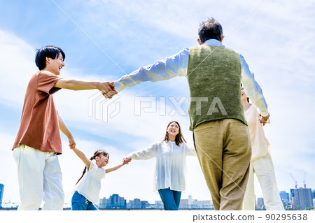 Three generations of families holding hands in a circle in the park 90295638
