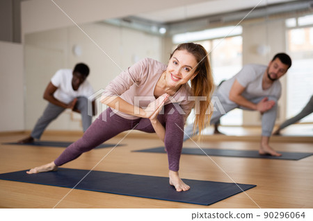 Woman and men practising yoga poses 90296064