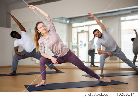 Woman doing Utthita Parsvakonasana during group yoga workout 90296114