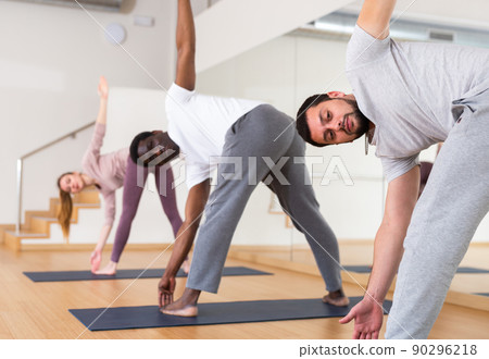 Men and woman doing windmill exercise in gym Men and woman doing windmill exercise in gym 90296218