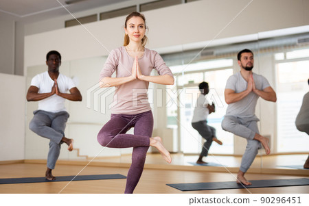 Woman standing in Eka Pada Utkatasana with hands clasped in prayer 90296451