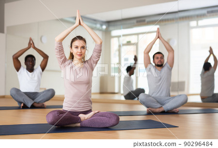 Woman and men practising lotus pose 90296484