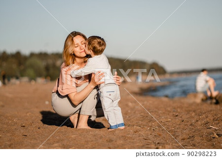 cute little caucasian boy kissing his young mother at the beach 90298223