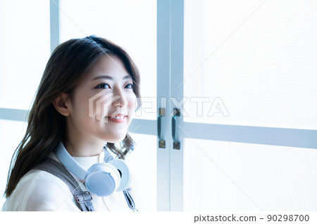 Young woman wearing headphones around her neck 90298700