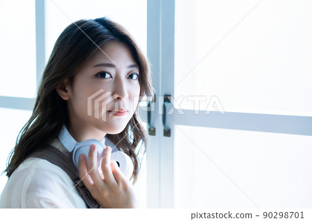 Young woman wearing headphones around her neck 90298701