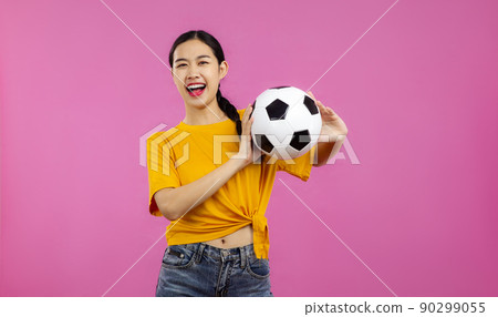 Happy Asian Girl football fan over isolated pink background holding a soccer ball and looking at camera, sport and people concept Happy Asian Girl football fan over isolated pink background holding a soccer ball and looking at camera, sport and people concept 90299055