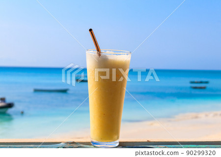 Glass of fresh juice by the ocean. Tropical vacations concept 90299320