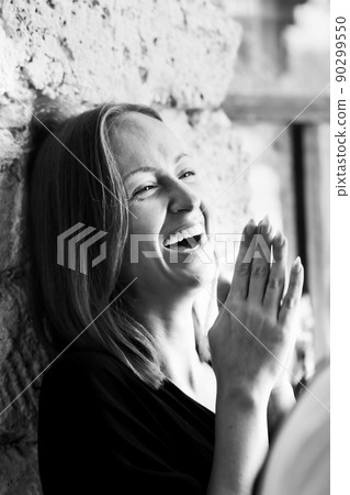 Black and white photograph of an attractive smiling woman. A large portrait on a stone background. Vertical photo. Black and white photograph of an attractive smiling woman. A large portrait on a stone background. Vertical photo. 90299550