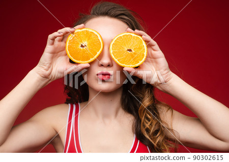 A beautiful woman in a red swimsuit with oranges 90302615