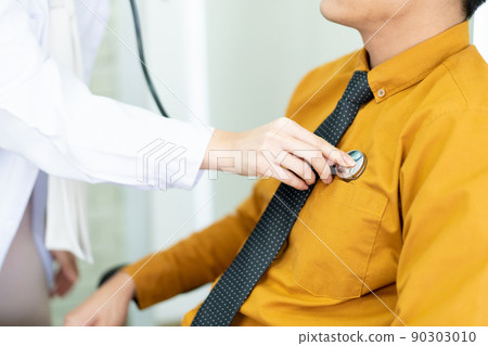 Doctor using stethoscope to listen patient's heartbeat and breathing. Heart attack prevention concept. Expertise cardiologist in hospital examine a heartbeat in male patient. 90303010