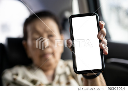 Asian old woman age 80 - 90 years old showing a blank screen smartphone, isolated with clipping path. Modern Asian grandmother concept with connectivity and internet technology. Empty white screen. 90303014