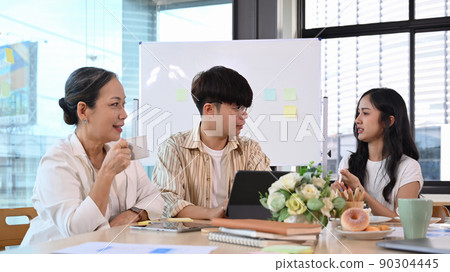 Attentive mature business team leader listening intently during discussion of business ideas with diverse employees at briefing Attentive mature business team leader listening intently during discussion of business ideas with diverse employees at briefing 90304445