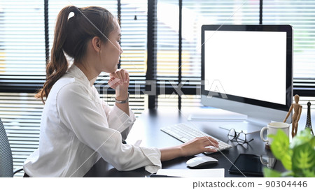 Side view thoughtful female manager looking at computer screen, working at modern workplace Side view thoughtful female manager looking at computer screen, working at modern workplace 90304446