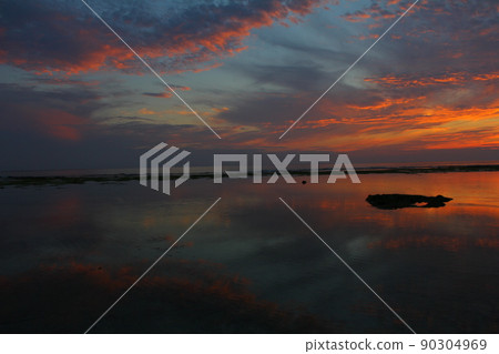 Sunset on a remote island reflecting off the surface of the sea 90304969