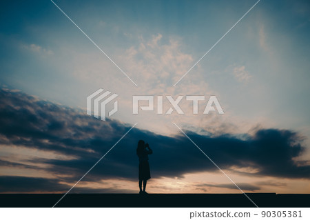 一個穿制服的高中女生的剪影和美麗的夕陽天空 90305381