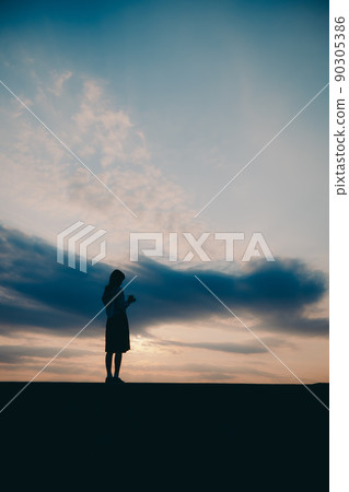 一個穿制服的高中女生的剪影和美麗的夕陽天空 一個穿制服的高中女生的剪影和美麗的夕陽天空 90305386