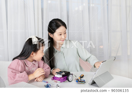 Asian Korean mother and daughter taking online classes on tablet 90306135