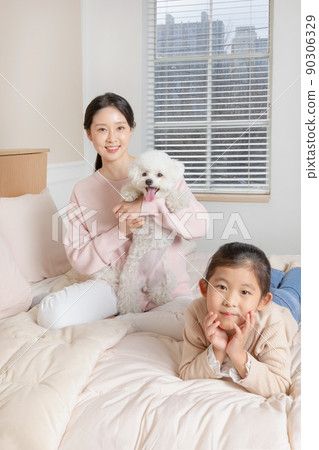 Asian Korean mother and daughter and puppy dog sitting on bed Asian Korean mother and daughter and puppy dog sitting on bed 90306329
