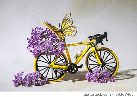 Yellow bike with lilac flowers and butterfly, creative background for the World Bicycle Day Yellow bike with lilac flowers and butterfly, creative background for the World Bicycle Day 90307405