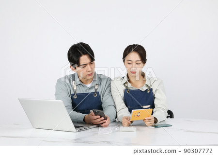 Asian Korean young man and woman startup concept_ looking at bankbooks and smartphones Asian Korean young man and woman startup concept_ looking at bankbooks and smartphones 90307772