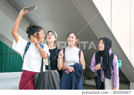 Group of young college women students laughing and taking selfie. 90309887