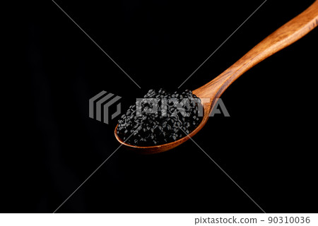 Wooden spoon with black caviar isolated on black background. Wooden spoon with black caviar isolated on black background. 90310036