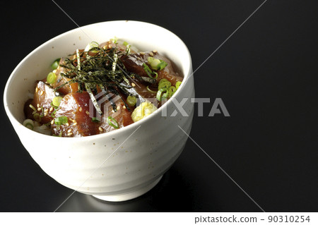 Photographed a bowl of pickled yellowtail with chopped seaweed, all-purpose greentail, and wasabi on a black background 90310254