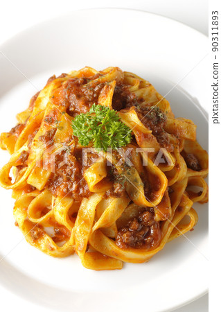 A bird's-eye view of Bolognese, which is often entwined with flat pasta fitcine and tomato sauce, on a white background. 90311893