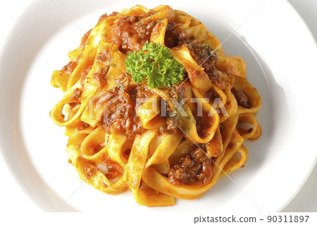 A bird's-eye view of Bolognese, which is often entwined with flat pasta fitcine and tomato sauce, on a white background. 90311897