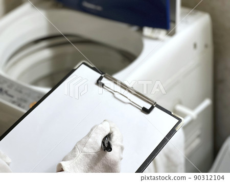 Hands of white gloves with a clipboard to assess the washing machine 90312104