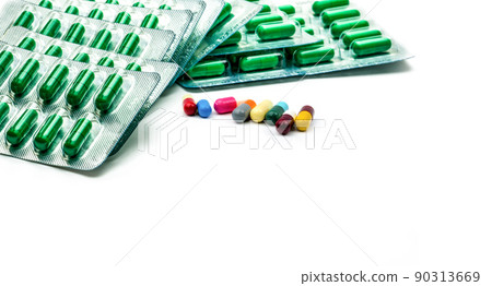 Green antibiotic capsule pill in blister pack and multicolored capsule pill on white background. Antibiotic drug resistance and prescription drugs concept. Pharmacy products. Pharmaceutical industry. Green antibiotic capsule pill in blister pack and multicolored capsule pill on white background. Antibiotic drug resistance and prescription drugs concept. Pharmacy products. Pharmaceutical industry. 90313669
