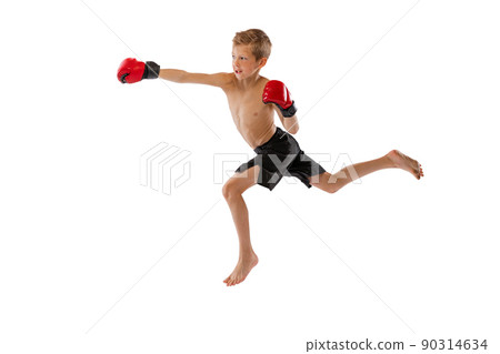 Punching. Little boy, kid in sports shots and gloves practicing thai boxing on white studio background. Sport, education, action, motion concept. 90314634