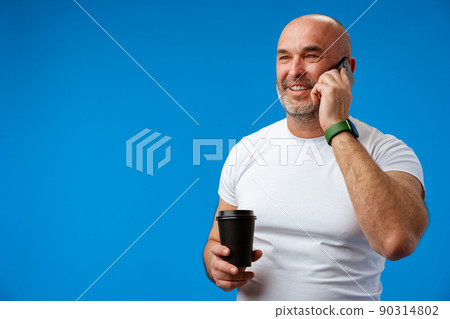 Portrait of an adult man talking on the phone against blue background. 90314802